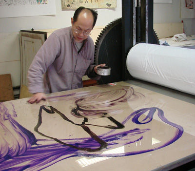 Photographie de Khoa Pham, artiste peintre, en train de réaliser une lithographie en grand format à l'atelier Pousse Caillou